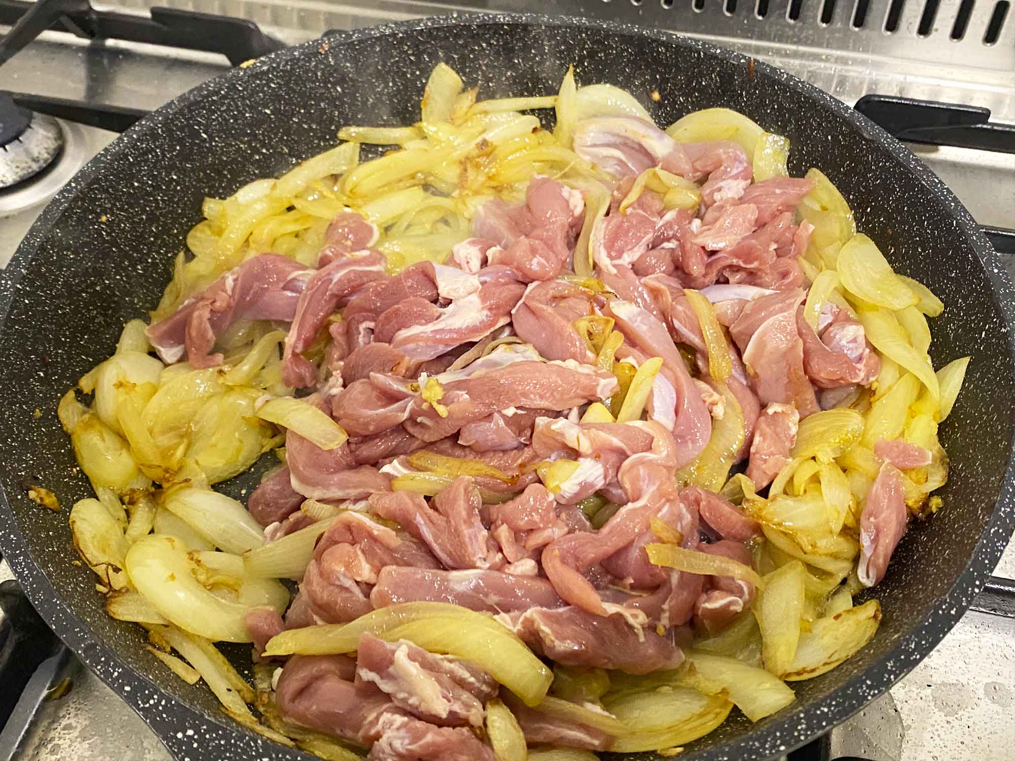 Chicken thigh strips added to the skillet